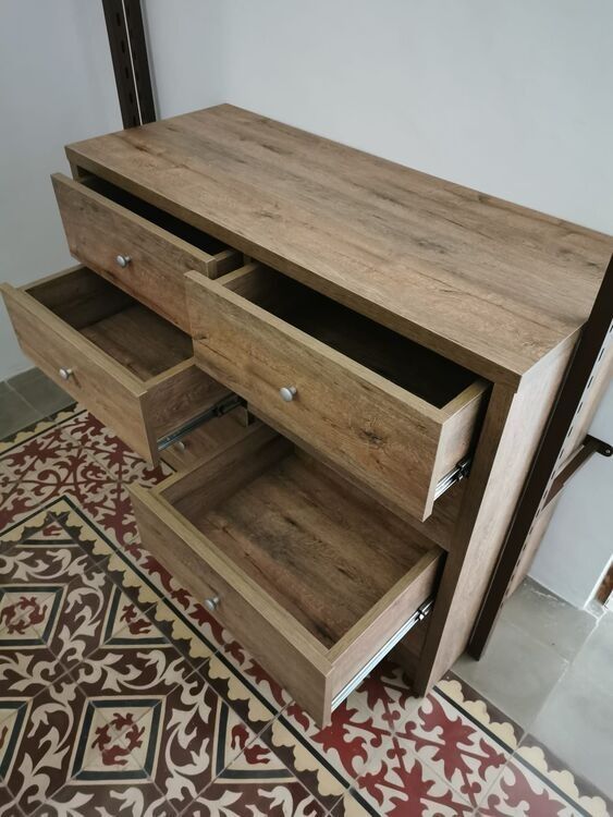 Una cómoda de madera con dos cajones abiertos sobre un suelo de baldosas.