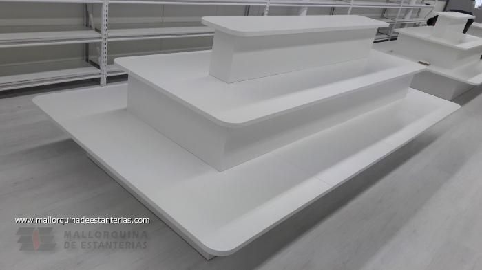 Tres mesas blancas están colocadas una encima de otra en una habitación.