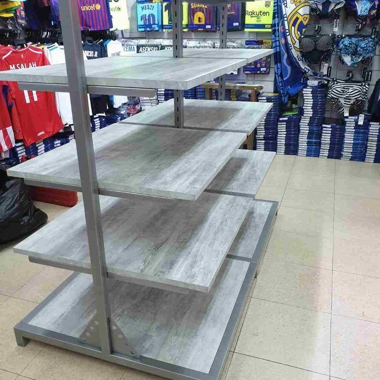 Una fila de estantes en una tienda con camisetas en la pared detrás de ellas.