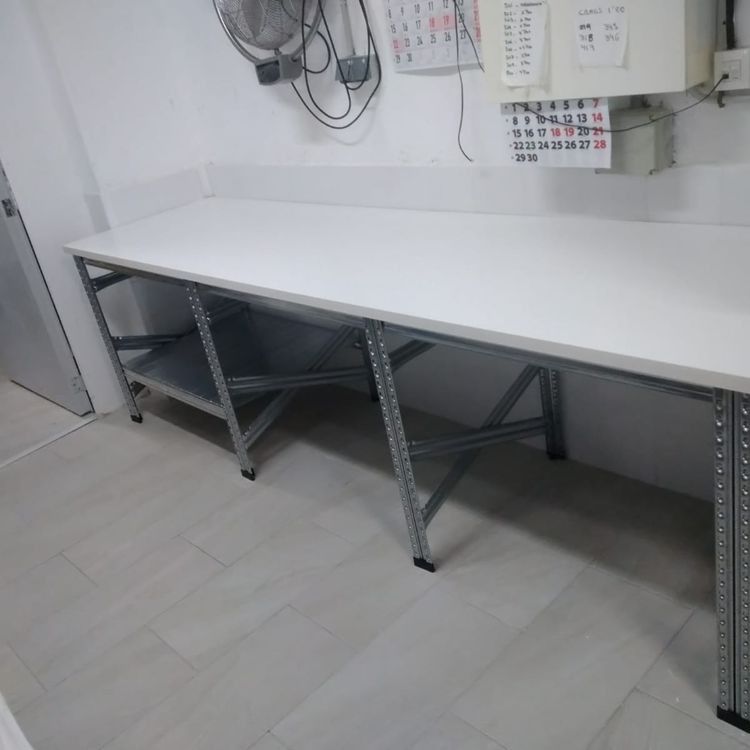 Una mesa blanca con marco de metal en una habitación con un calendario en la pared.