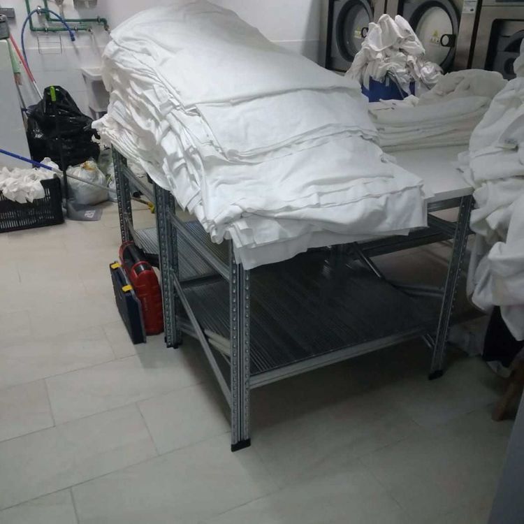 Una pila de sábanas blancas sobre una mesa en una lavandería.