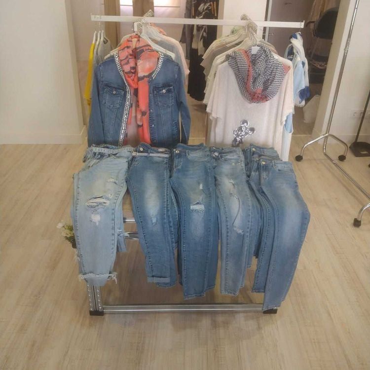 Una exhibición de jeans y camisas en un perchero