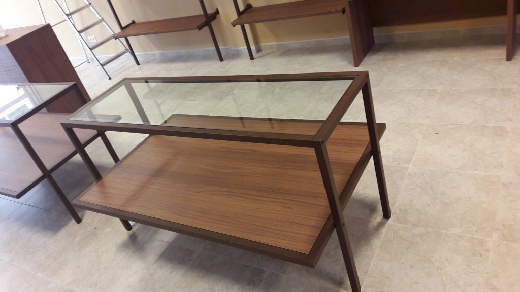 Una mesa de centro de cristal con un estante de madera debajo.