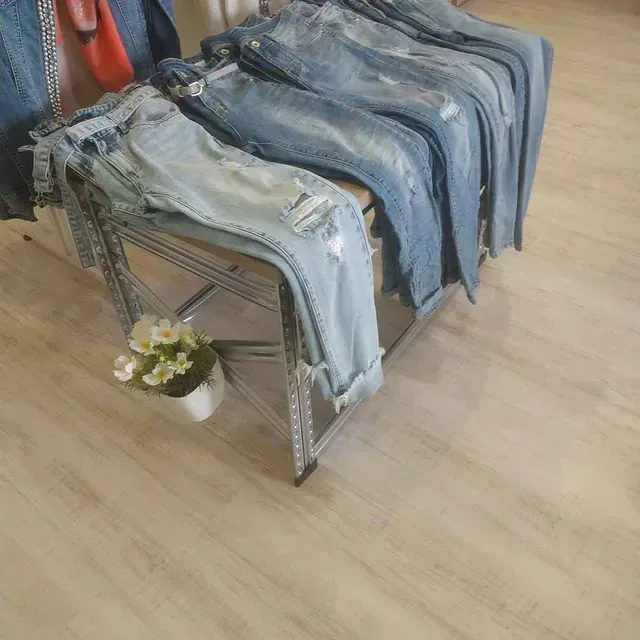 Una pila de jeans está sobre una mesa al lado de una planta en maceta.