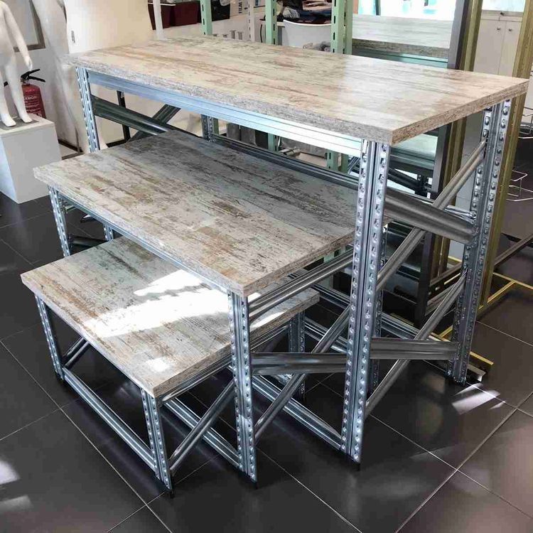 Un conjunto de tres mesas con tapas de madera están colocadas sobre un suelo de baldosas.