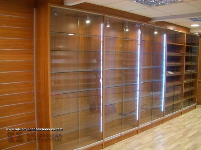 Una fila de estantes de vidrio con una pared de madera detrás de ellos.