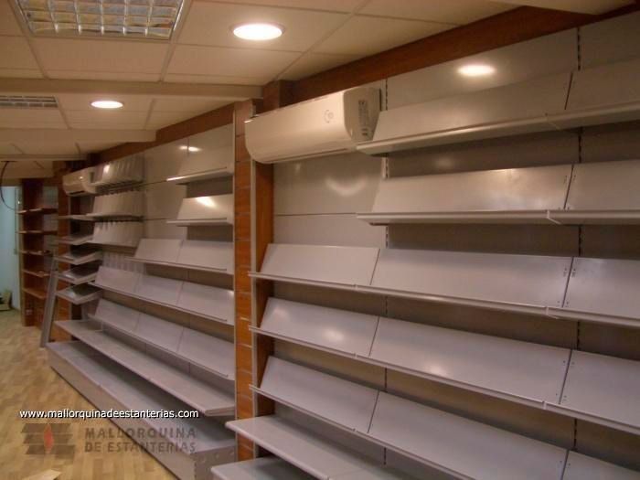 Una fila de estantes vacíos en una tienda con un sitio web en la pared.