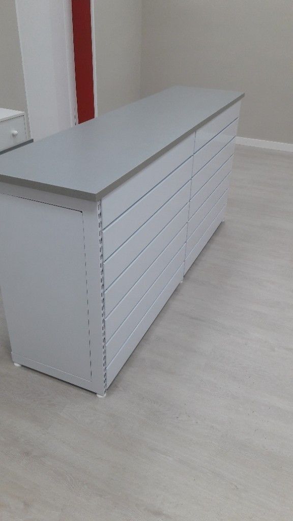 Una cómoda blanca larga se encuentra sobre un piso de madera en una habitación.