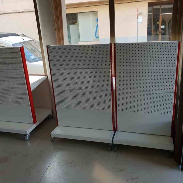 Una fila de estantes blancos con bordes rojos se encuentran frente a una ventana.