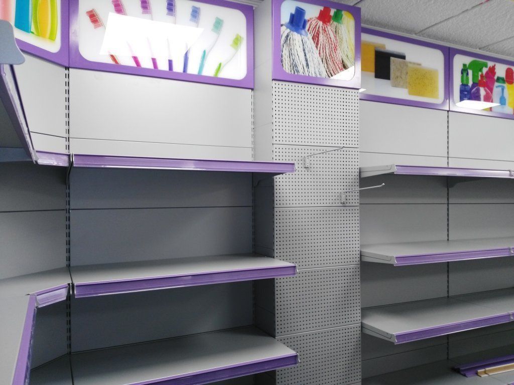 Estantes vacíos en una tienda con estantes morados y blancos.