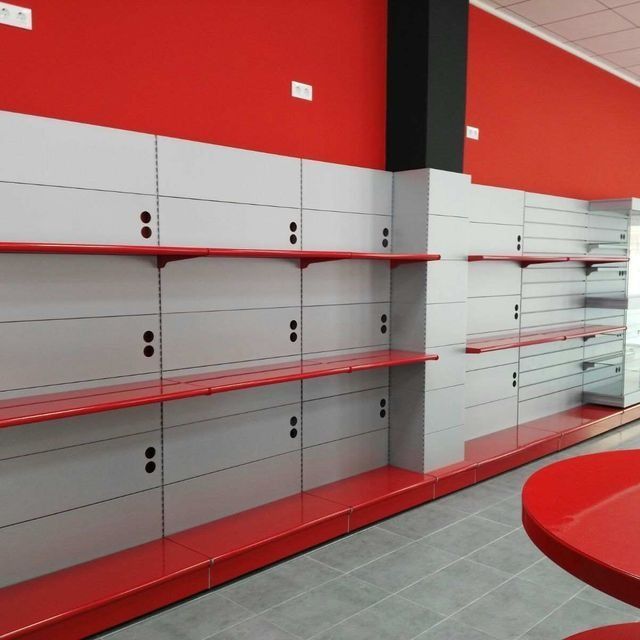 Una tienda vacía con estantes rojos y una mesa roja.