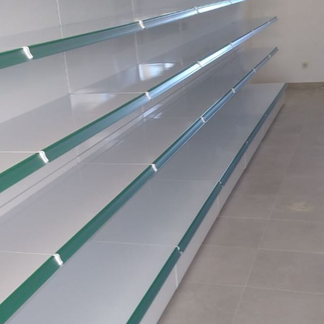 Una larga fila de estantes blancos con detalles verdes.