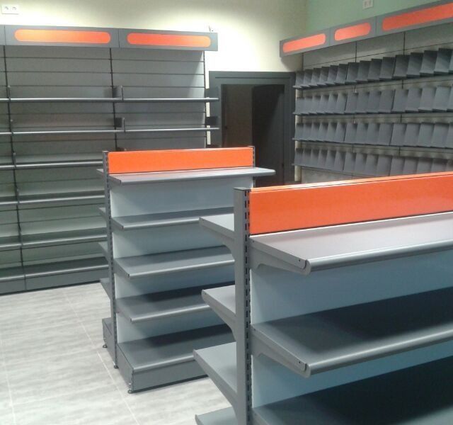 Estantes en una tienda con separadores naranjas entre ellos.