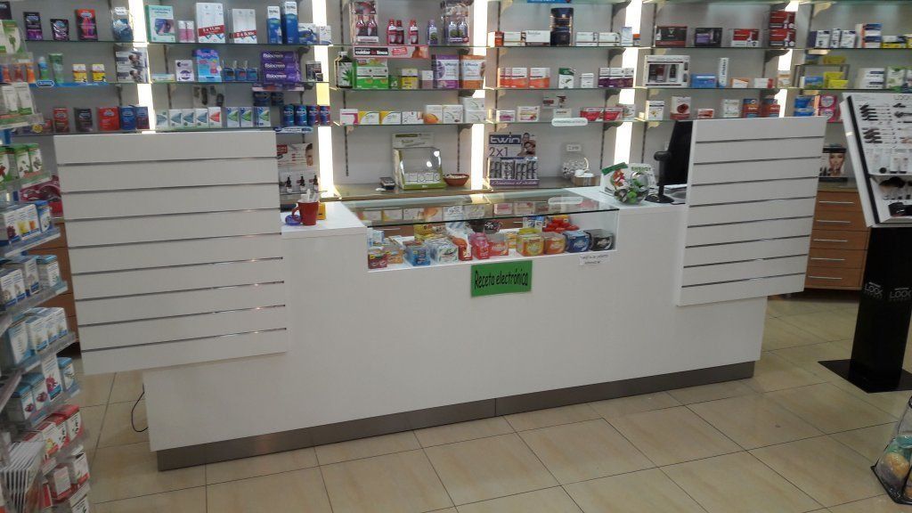El interior de una farmacia con un cartel verde en el mostrador.