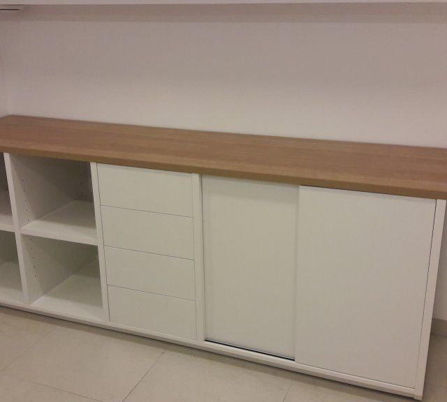 Un armario blanco con puertas corredizas y tapa de madera.