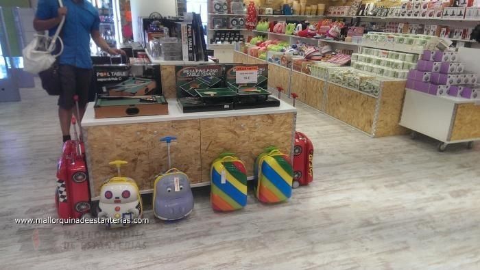 Un hombre está de pie en una tienda al lado de una mesa con equipaje sobre ella.