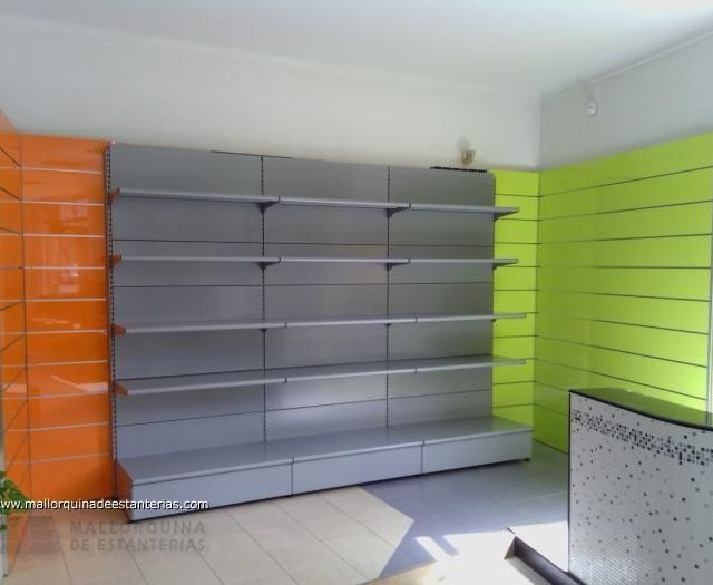 Una habitación vacía con estantes y paredes verdes y naranjas.