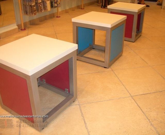 Una fila de taburetes coloridos sobre un suelo de baldosas.