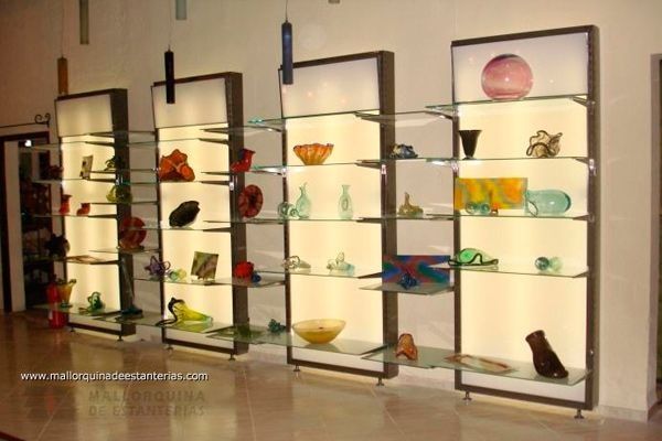 Una fila de estantes de vidrio con jarrones y cuencos sobre ellos.