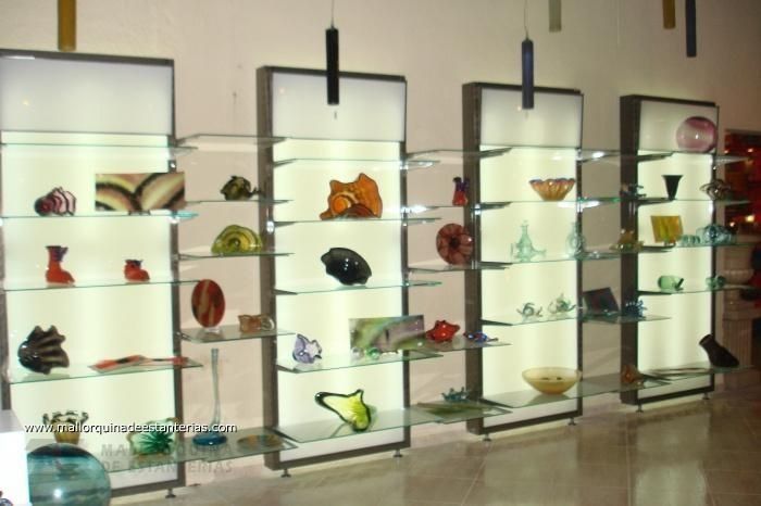 Una fila de estantes de vidrio con jarrones y cuencos sobre ellos.