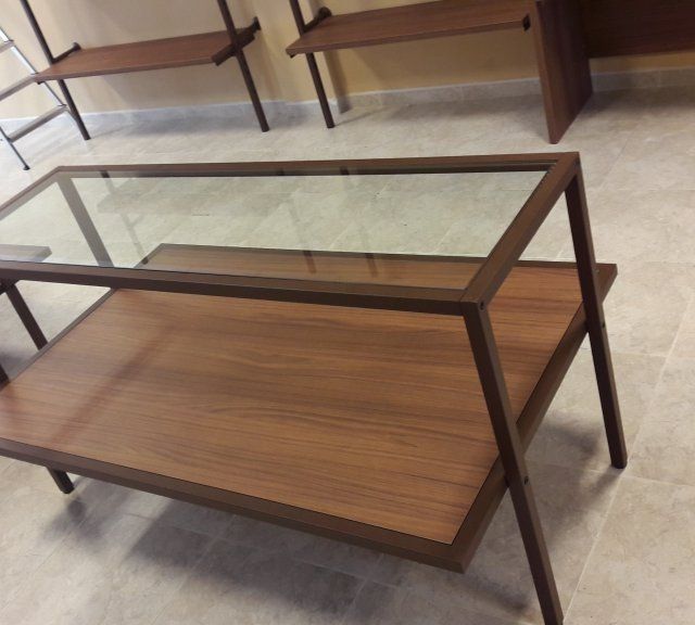 Una mesa de centro de cristal con un estante de madera debajo.