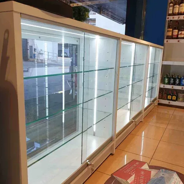 Una fila de estantes de vidrio en una tienda con libros en el suelo.