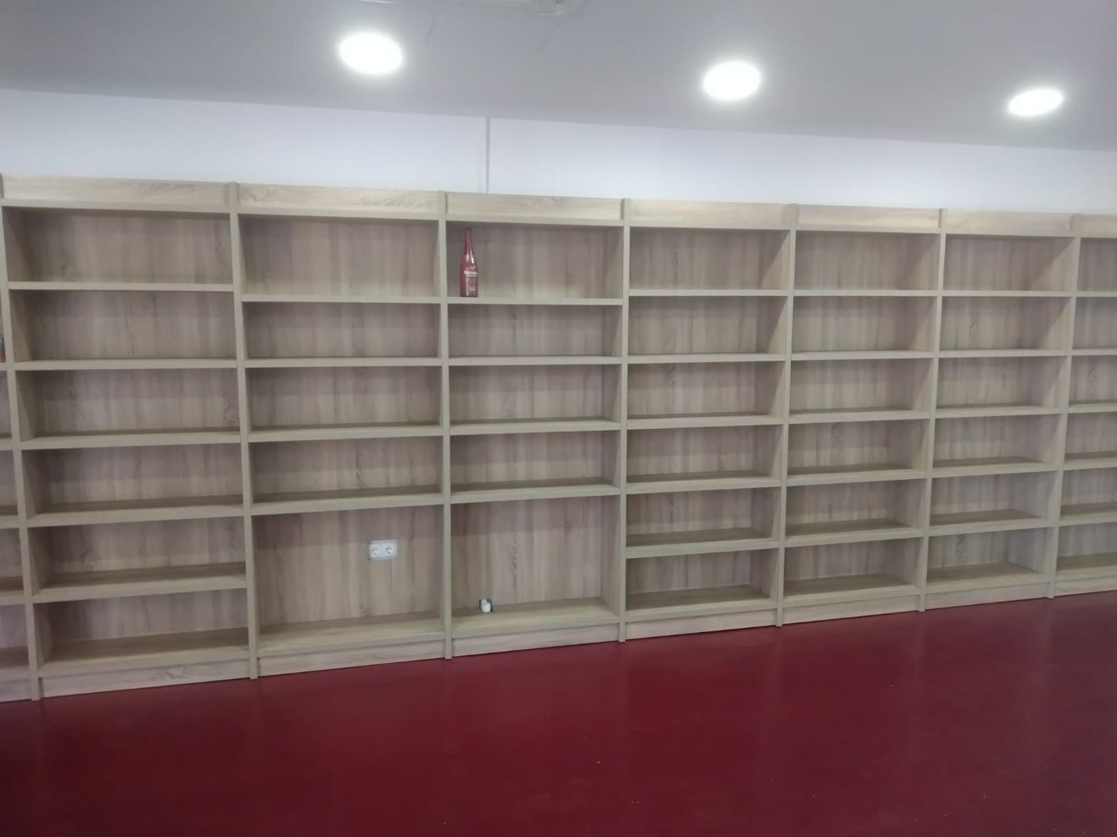 Una habitación con muchos estantes y un suelo rojo.
