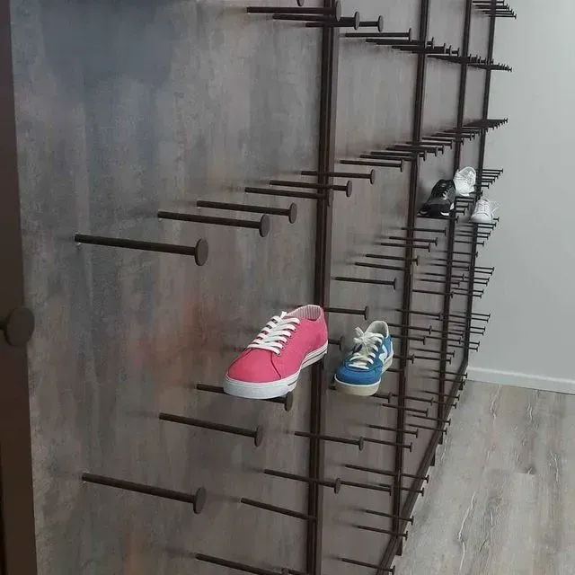 Un zapato rosa está colgado en una pared con clavos.