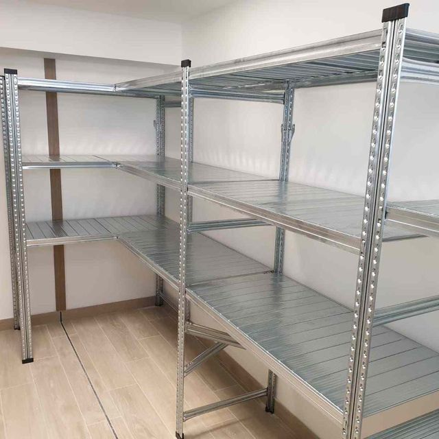 Una habitación con muchos estantes y suelo de madera.