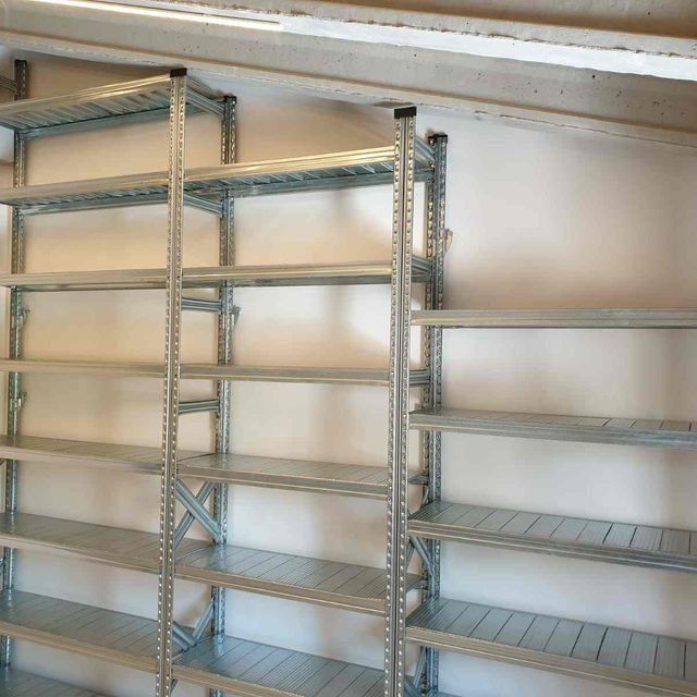 Una fila de estantes de metal contra una pared blanca.