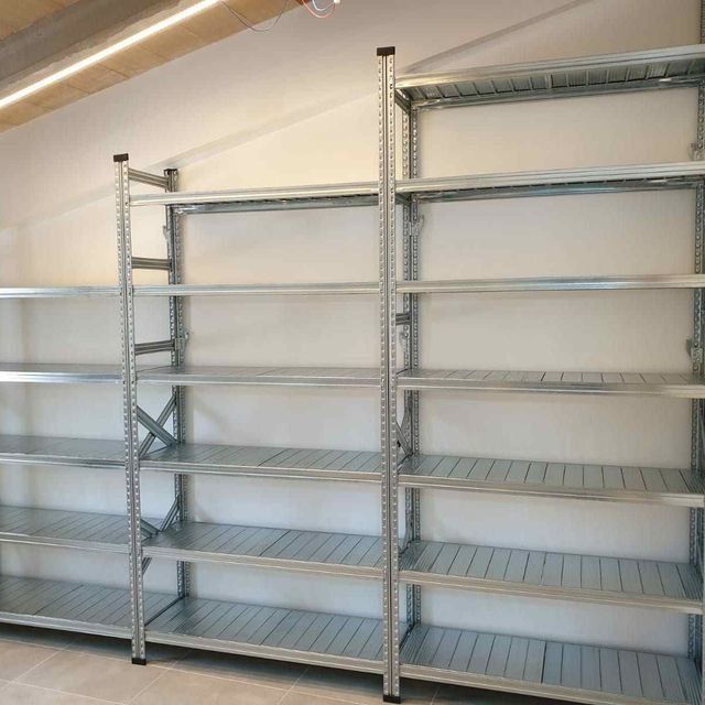 Una fila de estantes de metal contra una pared blanca.