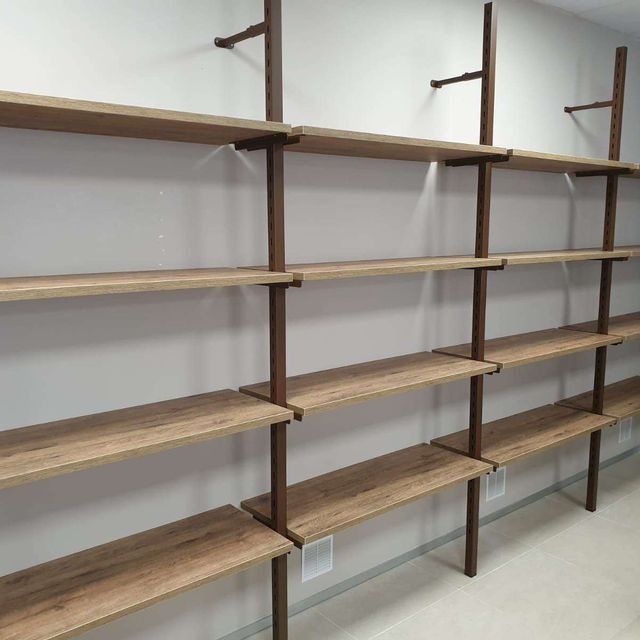 Una fila de estantes de madera contra una pared blanca.
