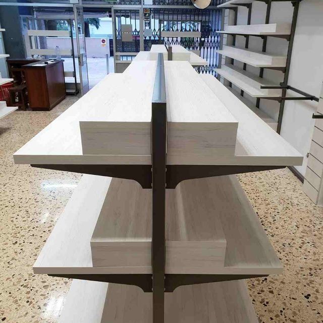 Una fila de estantes blancos en una tienda con una valla al fondo.