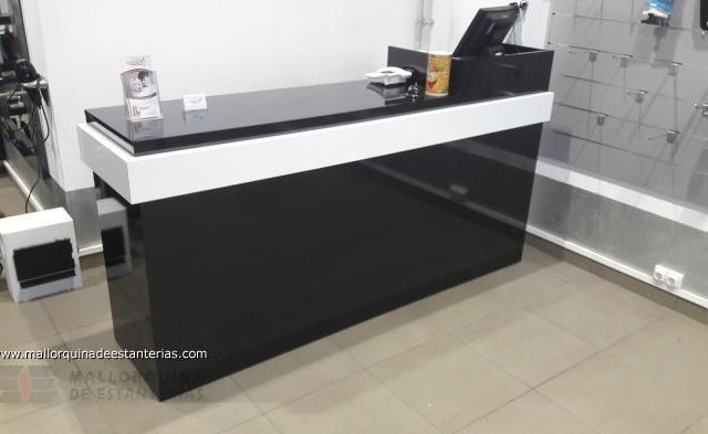 Un mostrador en blanco y negro en una habitación con una computadora encima.