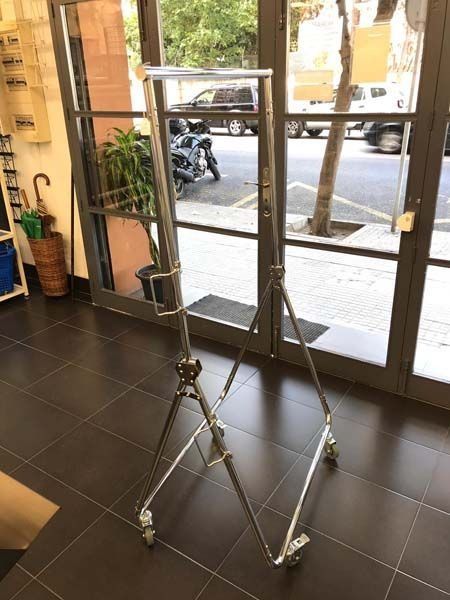 Un estante de metal con ruedas está situado delante de una puerta de cristal.