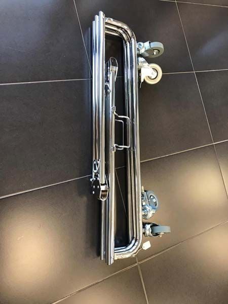 Un tubo de metal con ruedas está sobre un suelo de baldosas.