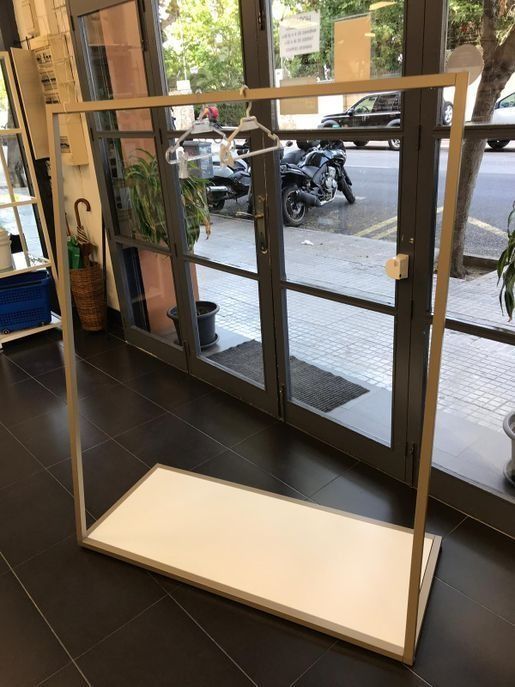 Un perchero está colocado delante de una puerta de cristal en una tienda.