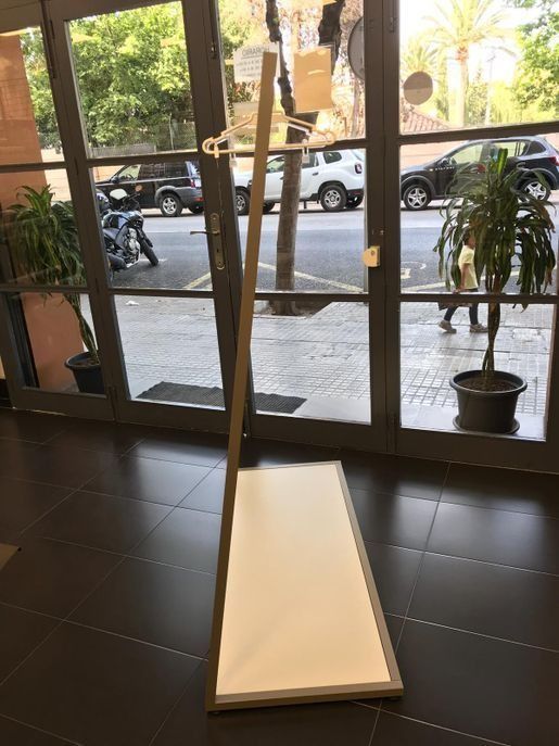 Una pizarra blanca está colocada sobre un suelo de baldosas delante de una puerta de cristal.