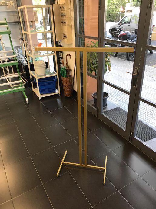 Un perchero dorado se encuentra en una habitación al lado de una puerta de cristal.