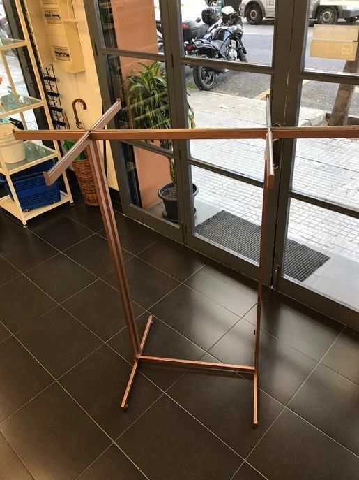 Un perchero de cobre reposa sobre un suelo de baldosas en una tienda.