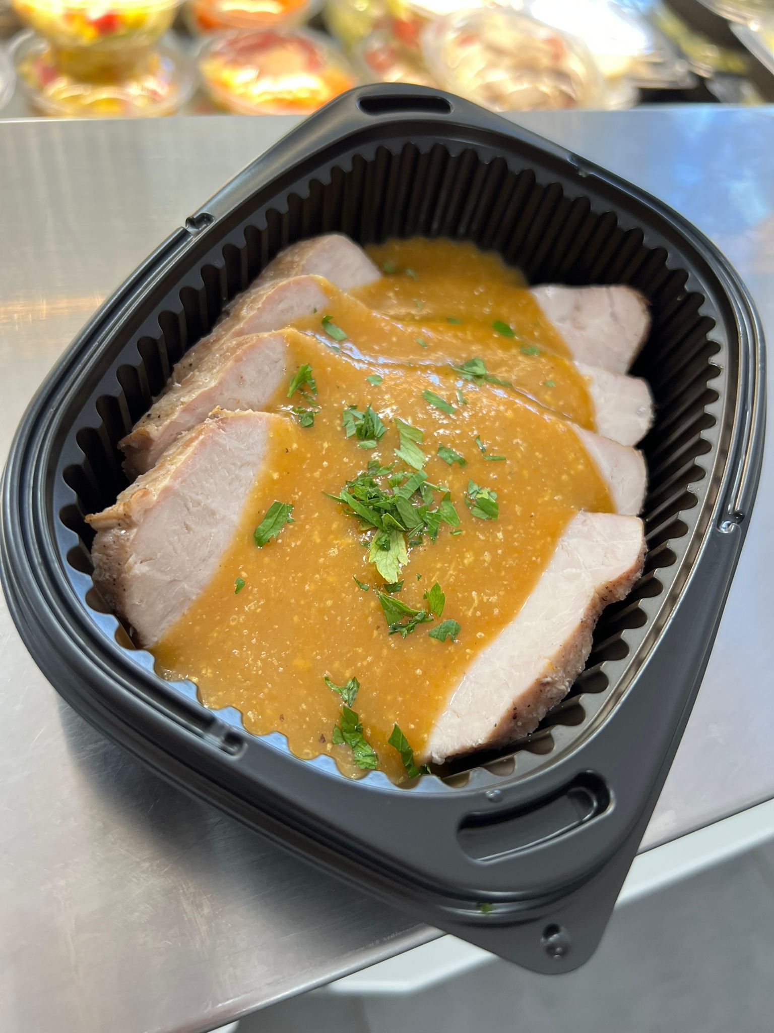 Un recipiente de plástico lleno de carne y salsa sobre una mesa.