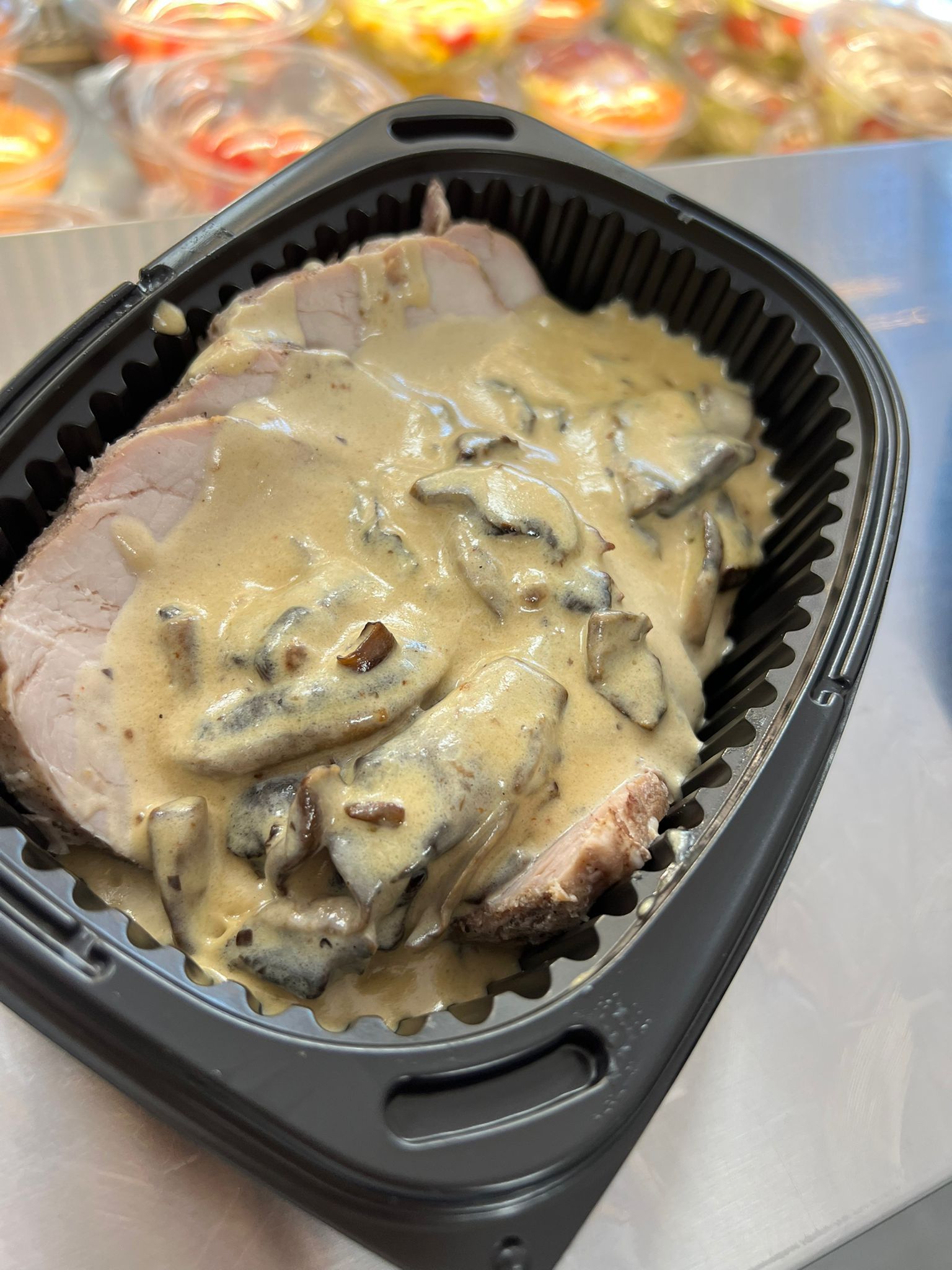 Un recipiente de plástico negro lleno de patatas cubiertas de salsa y caviar.