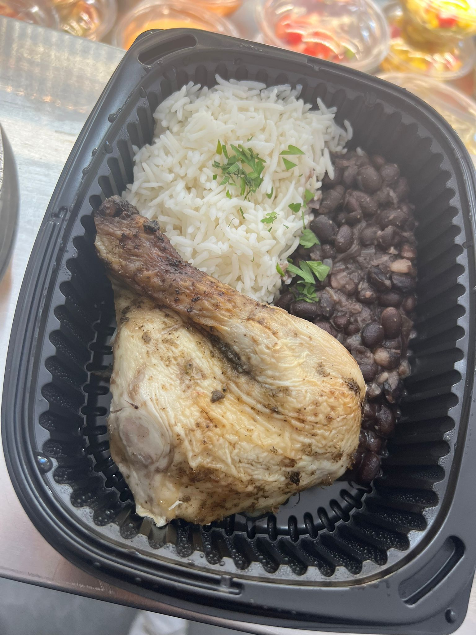 Un recipiente de plástico lleno de pollo, arroz y frijoles negros.