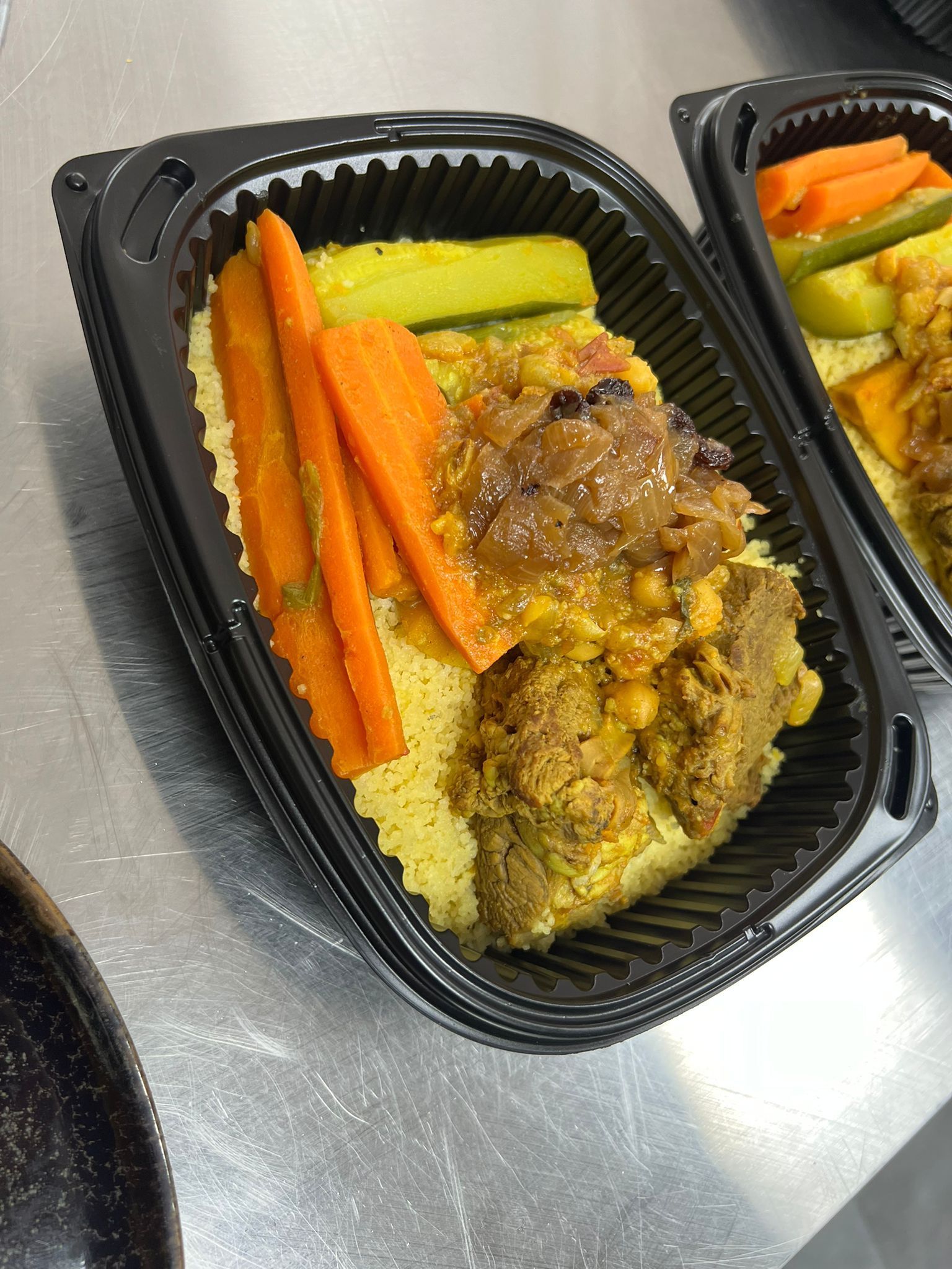 Un recipiente con comida con zanahorias y arroz sobre una mesa.
