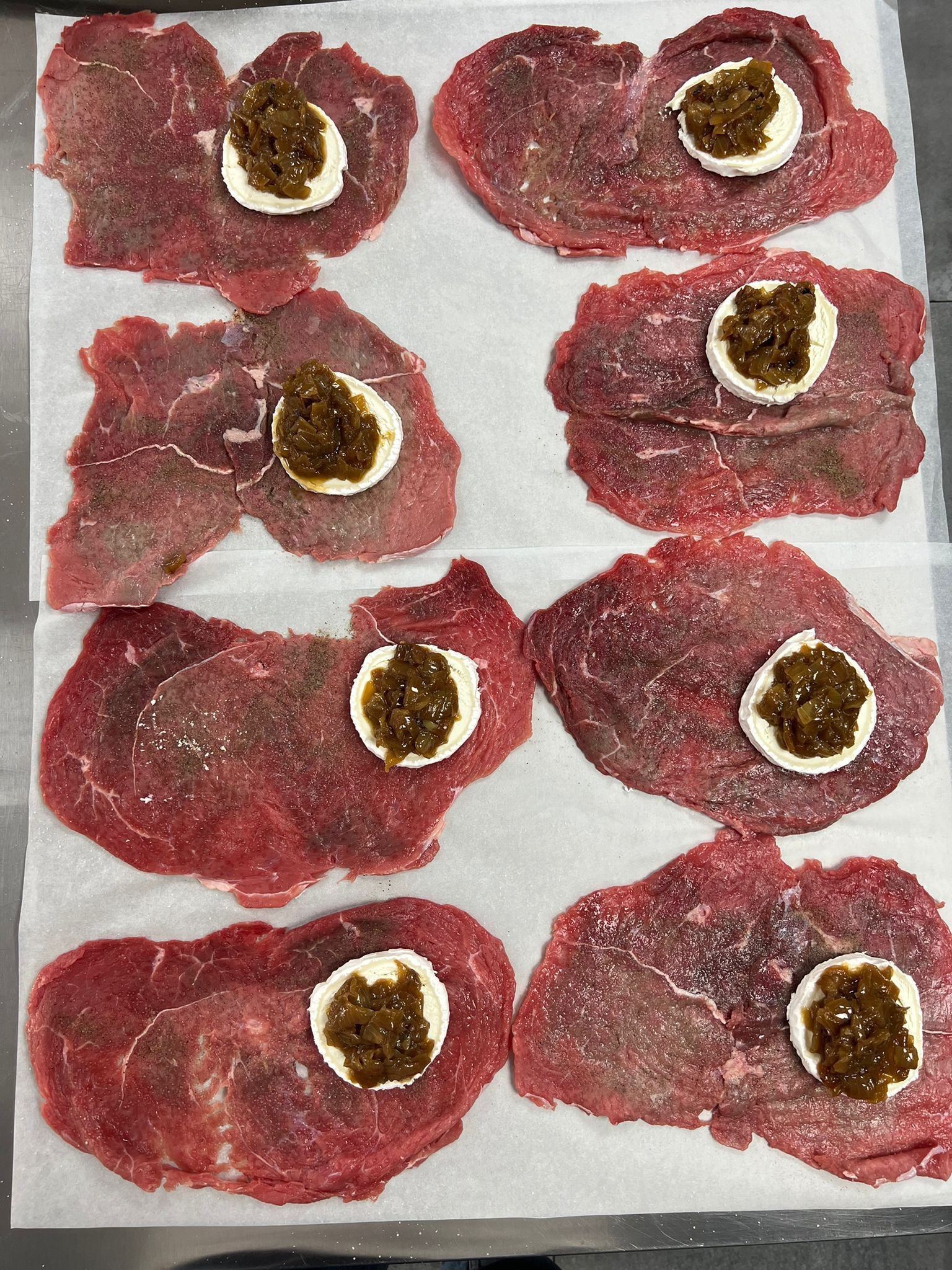 Un montón de rodajas de carne con salsa encima sobre una toalla de papel.