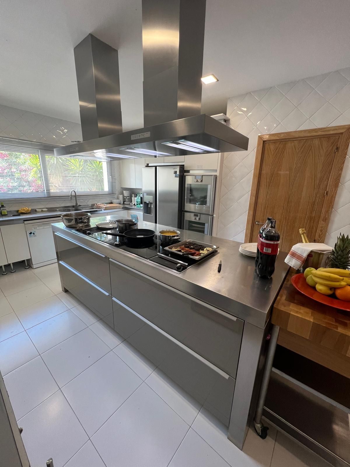 Una cocina con electrodomésticos de acero inoxidable y una botella de Coca Cola en la encimera.