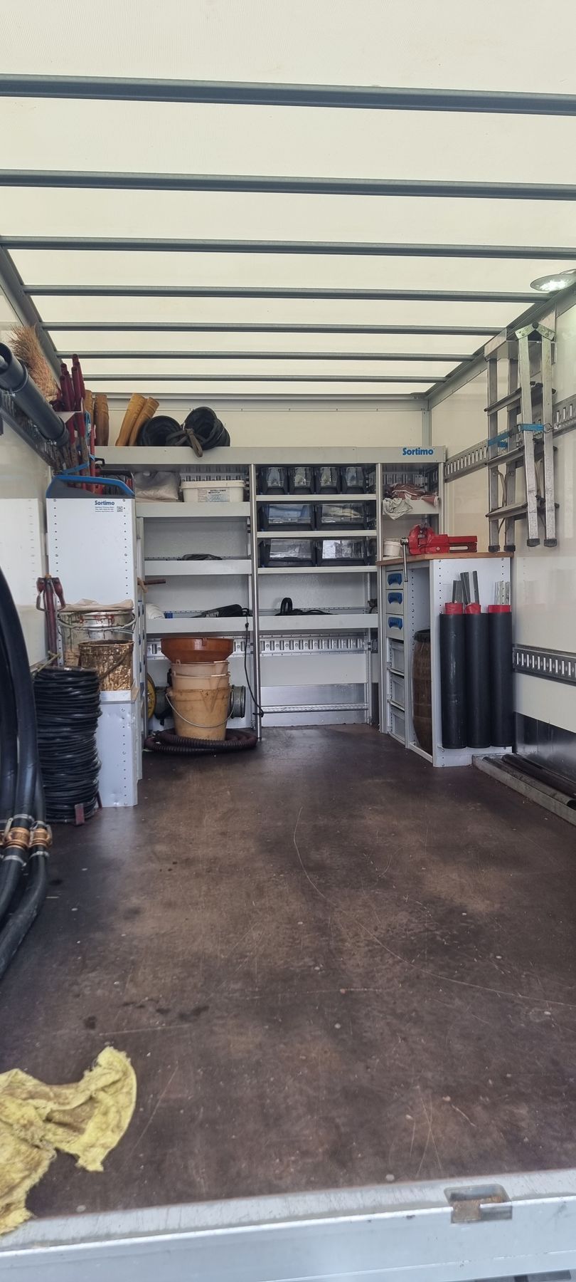 De grands réservoirs de stockage cylindriques blancs à l'extérieur, avec une échelle appuyée contre l'un d'eux sous un ciel bleu.