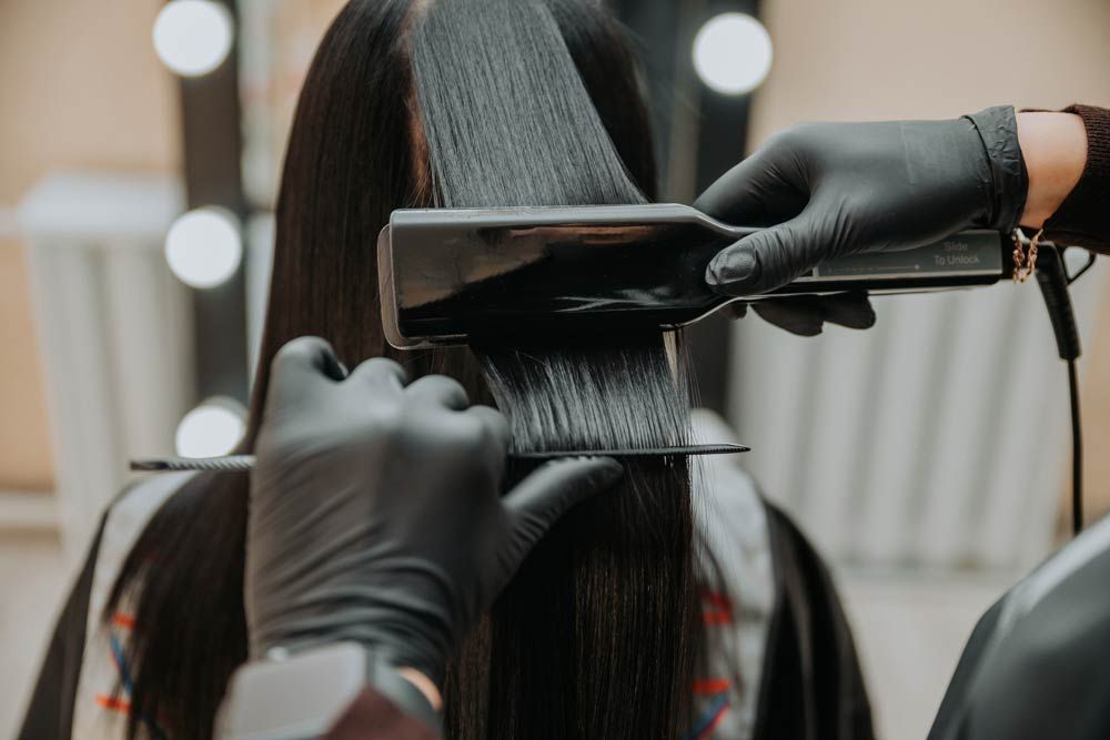 Una mujer se está alisando el cabello en una peluquería.