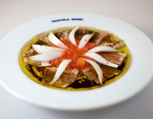 Un plato blanco con un tomate y una cebolla encima.