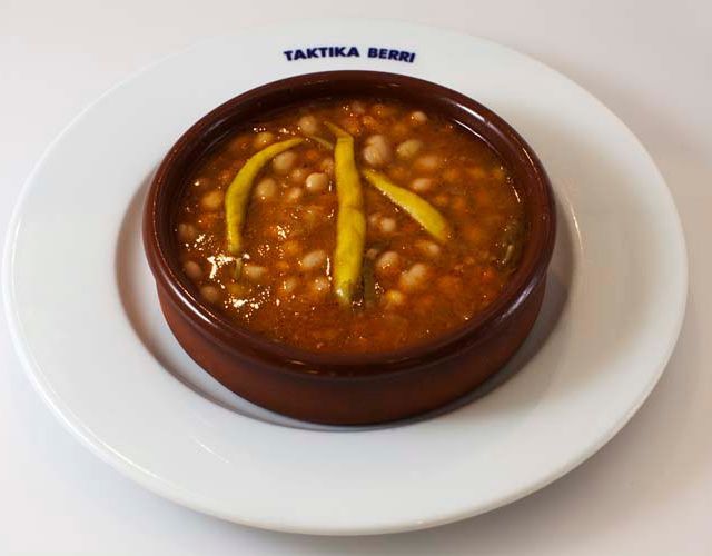 Un tazón de frijoles y pimientos en un plato que dice taktika berri